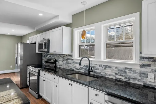 a kitchen with granite countertop a sink stainless steel appliances and cabinets