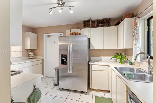 a kitchen with stainless steel appliances a refrigerator sink and white cabinets