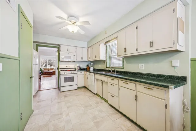 a large white kitchen with granite countertop a sink a window and stainless steel appliances