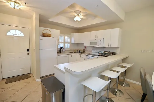 a kitchen with stainless steel appliances a sink a refrigerator a stove a dining table and chairs