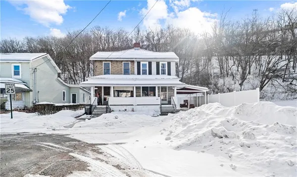 a front view of a house with a yard covered in snow