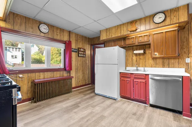 a kitchen with refrigerator a window and wooden cabinets