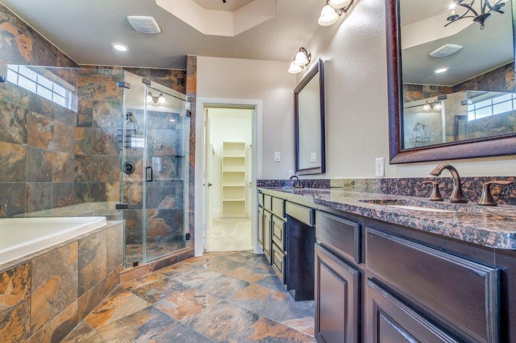 46 East Rafters Row The Woodlands, TX 77380 - Photo 14 of 25 Spa-inspired primary bath with dual granite vanities, oversized glass shower, soaking tub, and elegant finishes.