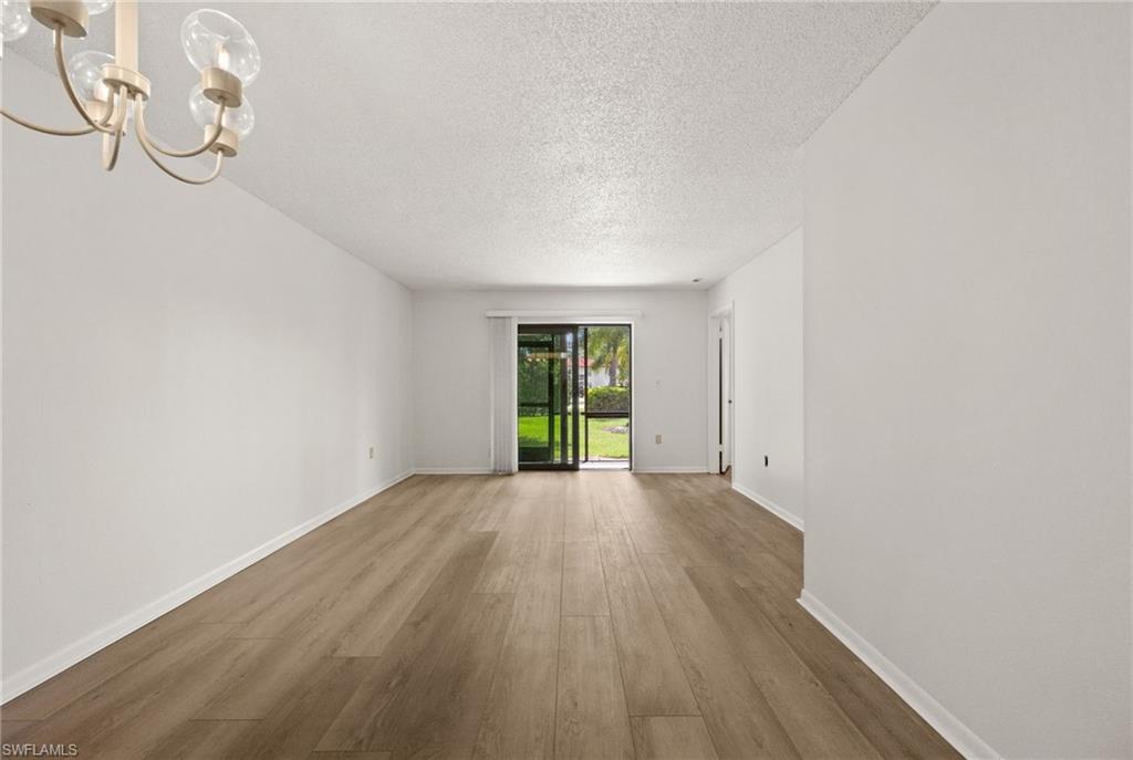 4251 27th Court Southwest, Unit 104 Naples, FL 34116 - Photo 5 of 22 a view of an empty room with wooden floor and windows