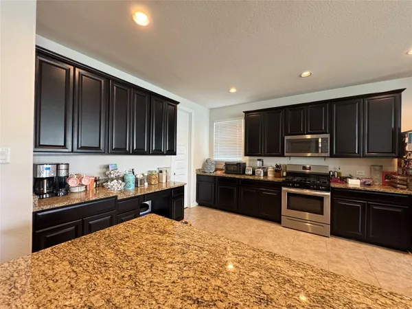 a kitchen with granite countertop wooden cabinets and black appliances