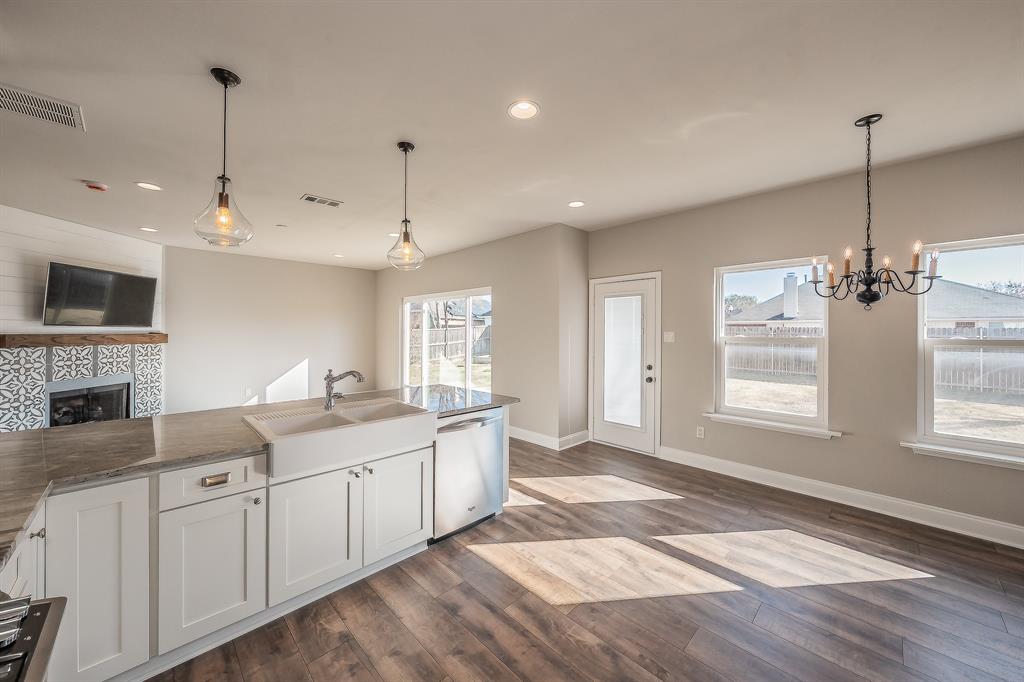 7305 Raintree Way Denton, TX 76210 - Photo 11 of 32 a large white kitchen with granite countertop a stove and a sink