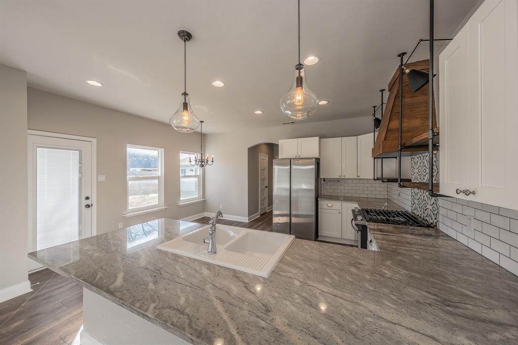 7305 Raintree Way Denton, TX 76210 - Photo 10 of 32 a kitchen with stainless steel appliances kitchen island granite countertop a sink a stove and a refrigerator