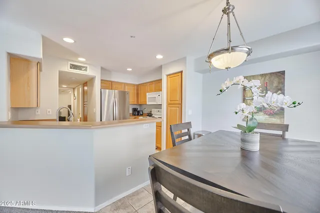 a kitchen with stainless steel appliances granite countertop a stove a refrigerator a sink a dining table and chairs with wooden floor