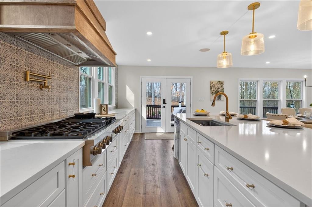 16145 Henderson Road Alpharetta, GA 30004 - Photo 20 of 61 a kitchen with stainless steel appliances a stove a sink dishwasher and white cabinets with wooden floor