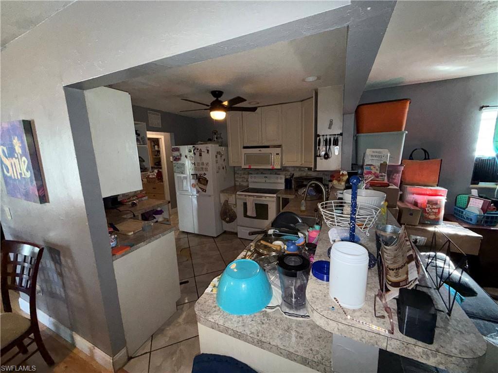 117 Robert Avenue Lehigh Acres, FL 33936 - Photo 4 of 20 Kitchen featuring white appliances, light tile patterned flooring, ceiling fan, and white cabinets