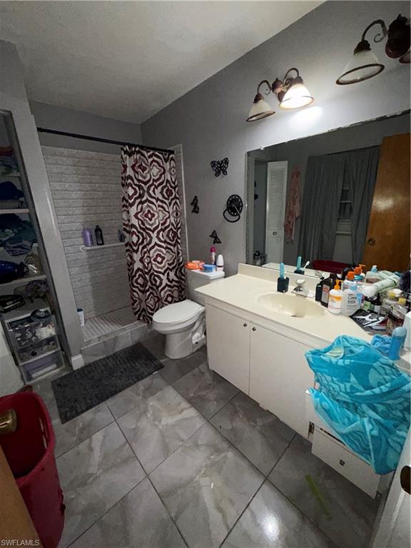 117 Robert Avenue Lehigh Acres, FL 33936 - Photo 9 of 20 Bathroom featuring a stall shower, vanity, light marble finish floors, and a walk in closet