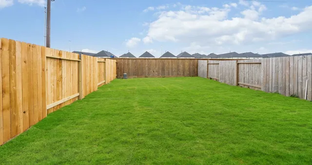 a view of a yard with wooden fence