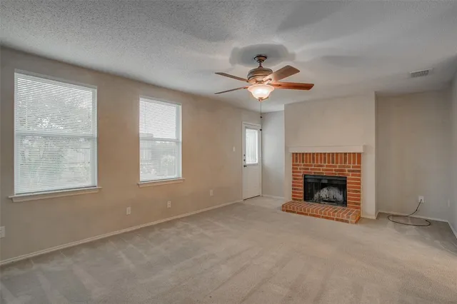 an empty room with windows and fireplace