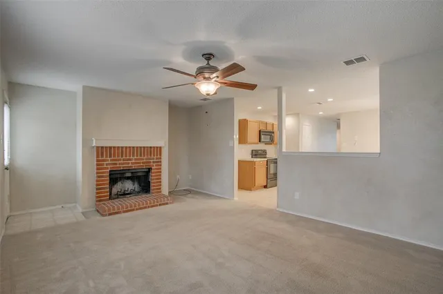 an empty room with chandelier fan and fire place