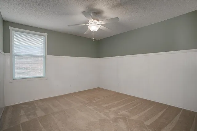 an empty room with a chandelier fan and windows