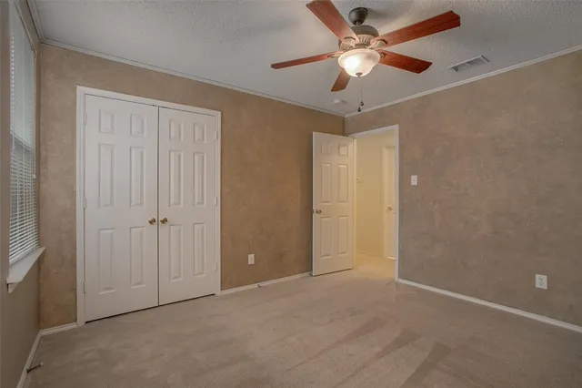 an empty room with closet and a ceiling fan