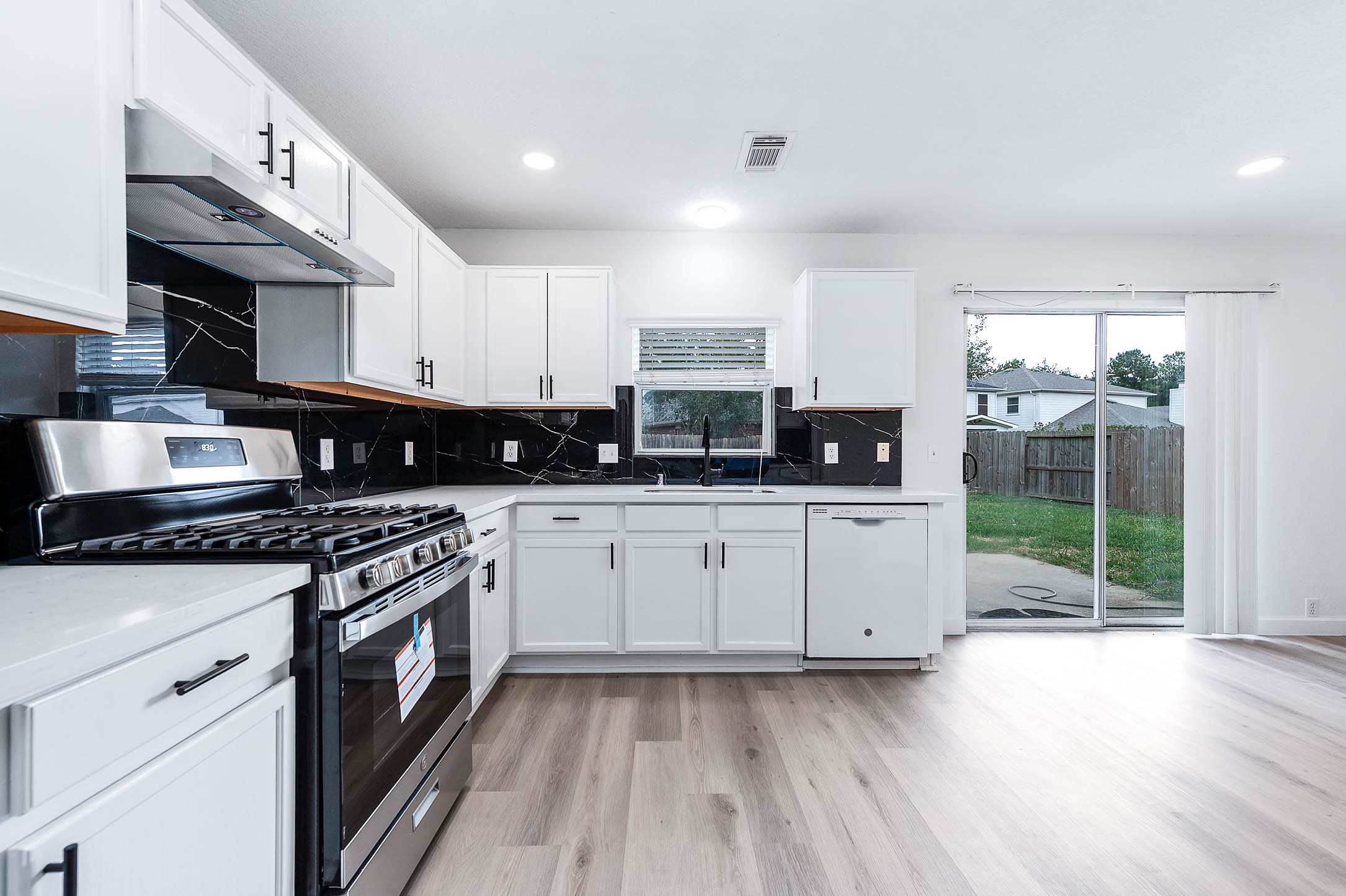 a kitchen with stainless steel appliances granite countertop a stove a sink and white cabinets