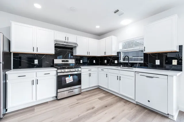 a kitchen with stainless steel appliances granite countertop a stove a sink and white cabinets