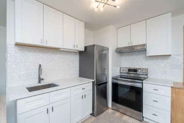 a kitchen with white cabinets and stainless steel appliances