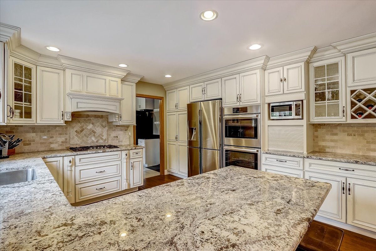 4365 Phyllis Drive Northbrook, IL 60062 - Photo 23 of 55 a kitchen with stainless steel appliances granite countertop a refrigerator a stove and a sink with wooden floor
