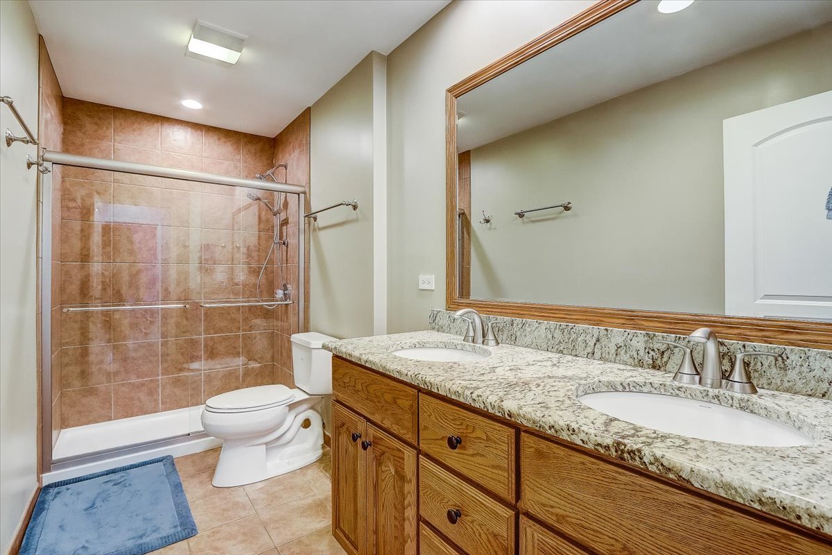 4365 Phyllis Drive Northbrook, IL 60062 - Photo 39 of 55 a bathroom with a granite countertop sink a toilet a mirror and shower