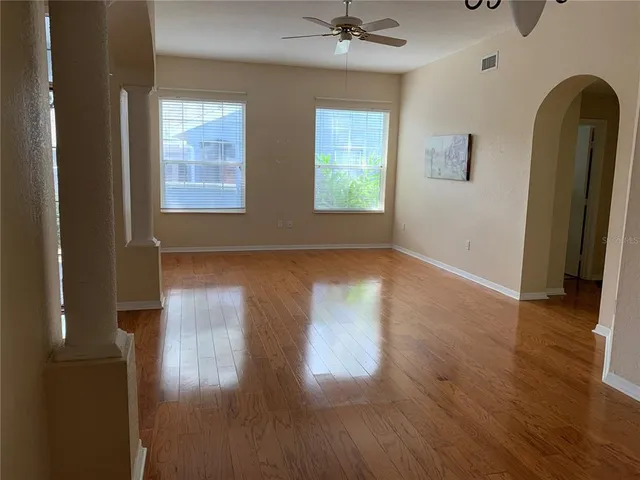 an empty room with wooden floor and windows