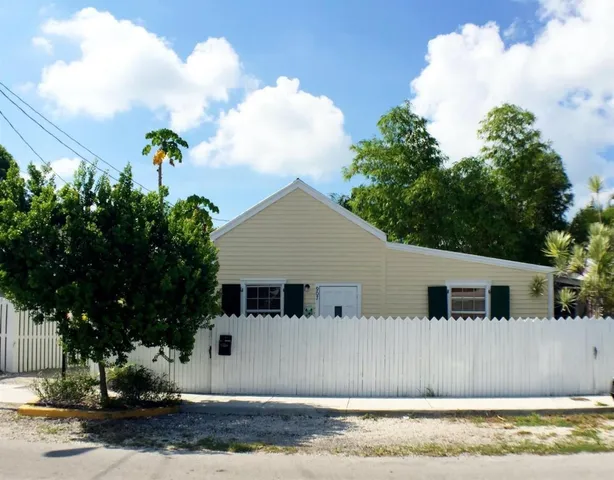 a front view of a house with a yard and a large tree