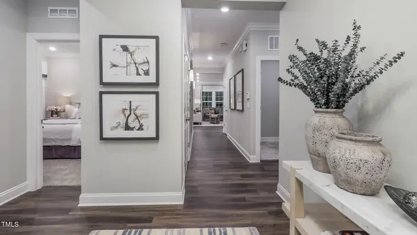 a view of a hallway with wooden floor and paintings on the wall