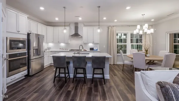 a dining room with stainless steel appliances kitchen island granite countertop a dining table chairs and a refrigerator