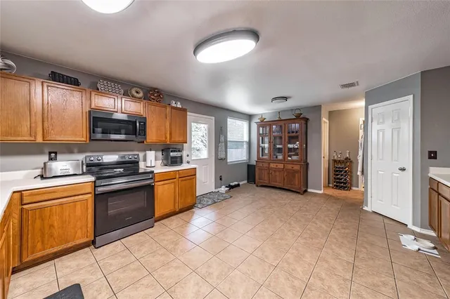 a large kitchen with stainless steel appliances granite countertop a stove top oven a sink dishwasher and a microwave oven on the blue kitchen countertops