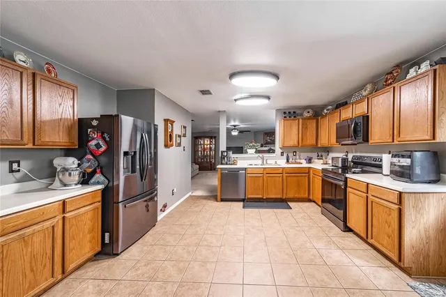 a large kitchen with stainless steel appliances kitchen island granite countertop a stove refrigerator and a sink