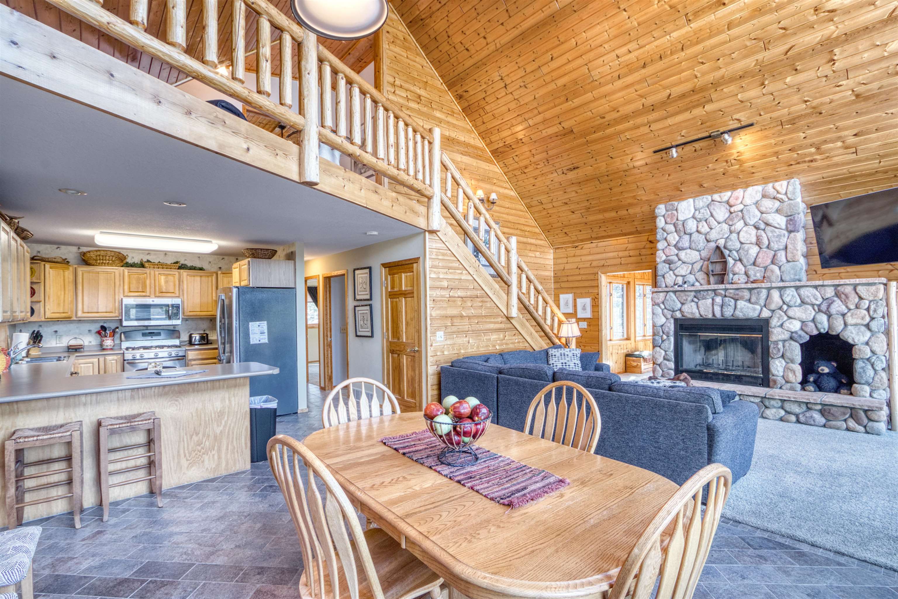 14366 North One Mile Road Minong, WI 54859 - Photo 16 of 40 Dining area featuring wood ceiling, stairway, stone finish flooring, a fireplace, and high vaulted ceiling