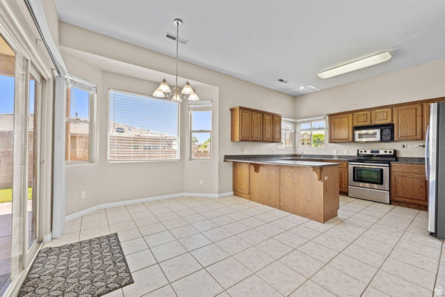2226 East 140 South St. George, UT 84790 - Photo 6 of 20 Kitchen and dining area featuring tile flooring, wood cabinetry, stainless steel appliances, and a breakfast bar