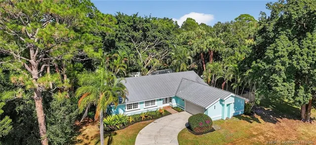 an aerial view of a house with yard and trees in the background