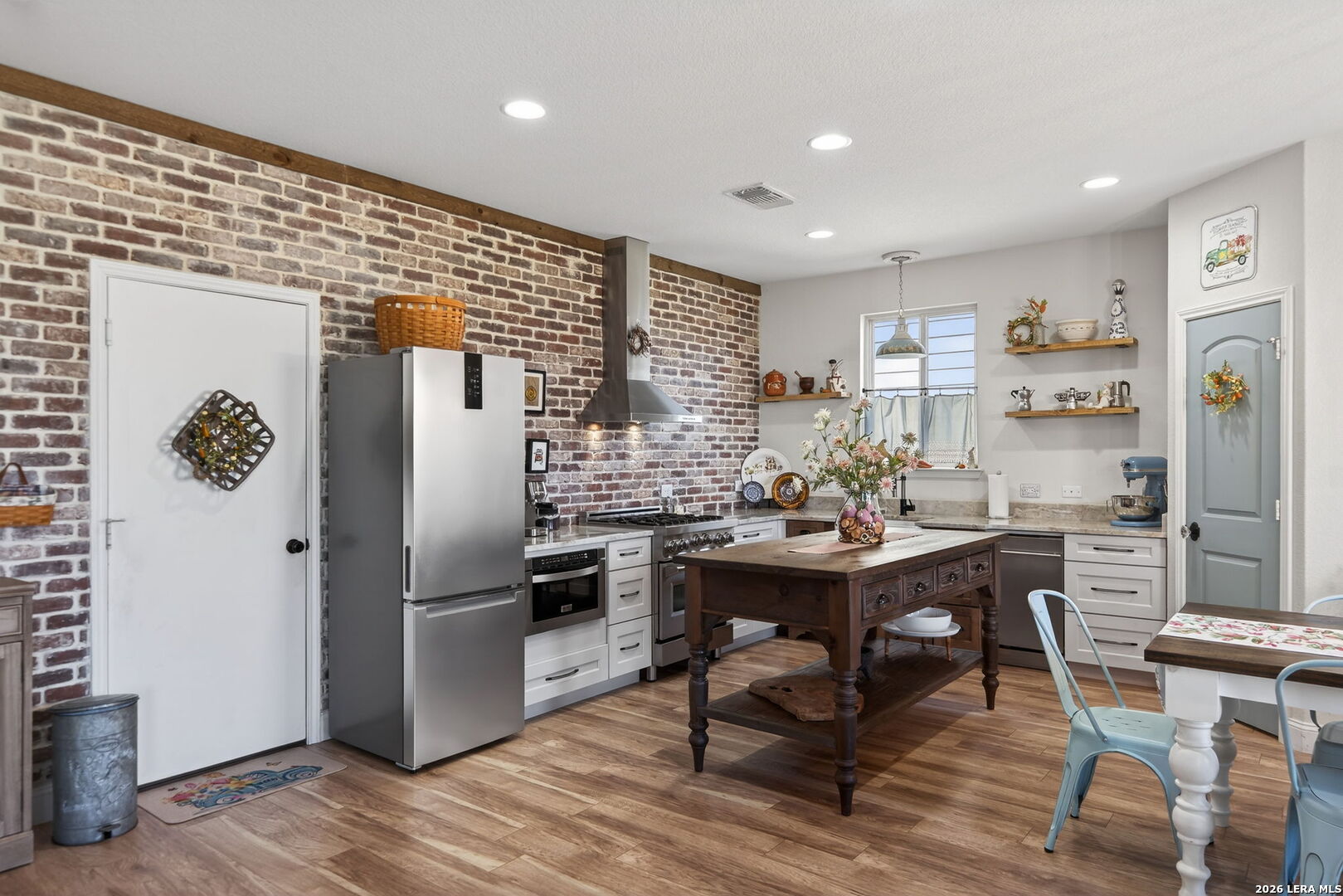 613 Whitman Avenue Georgetown, TX 78626 - Photo 7 of 24 a kitchen with stainless steel appliances kitchen island granite countertop a refrigerator a stove a sink and chairs with wooden floor