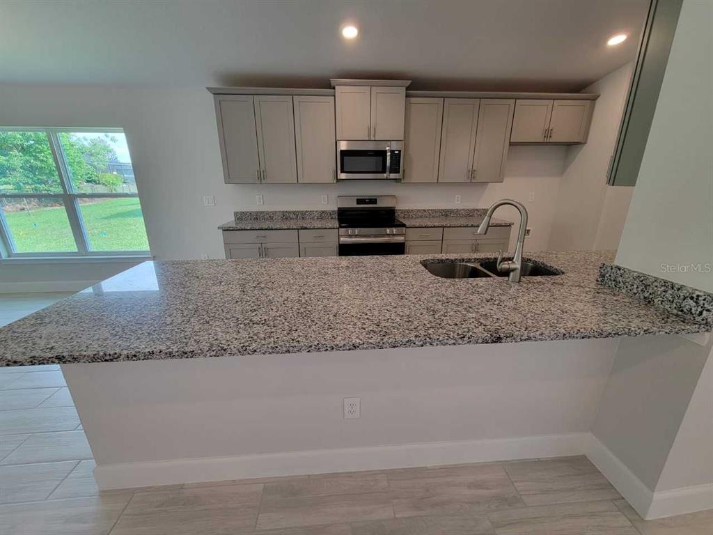 4525 Southwest 91st Ln Road Ocala, FL 34476 - Photo 7 of 20 a kitchen with granite countertop a sink window and cabinets