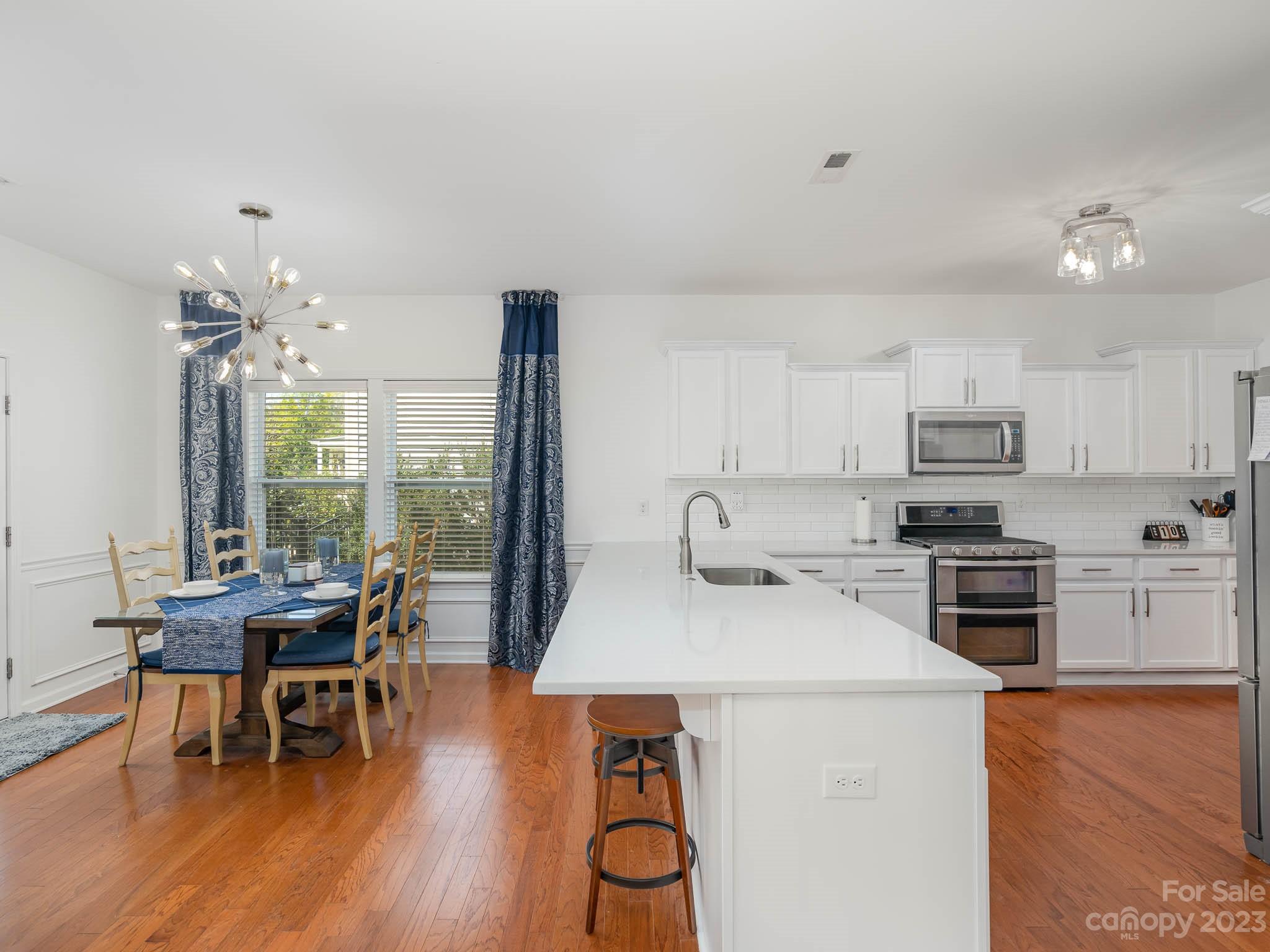 2185 Bluebell Way Tega Cay, SC 29708 - Photo 12 of 45 a kitchen with stainless steel appliances granite countertop a stove top oven a dining table and chairs with wooden floor