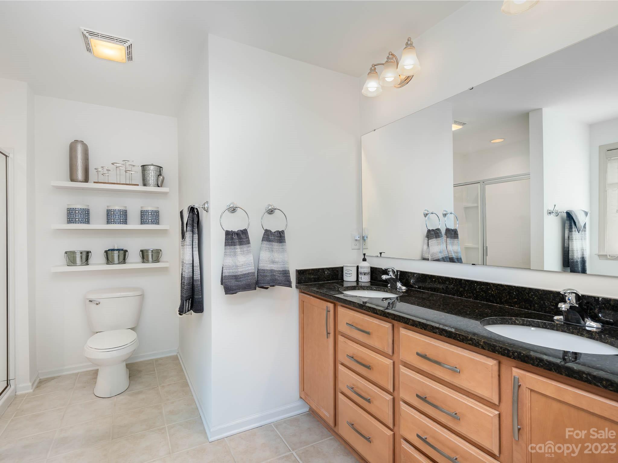 2185 Bluebell Way Tega Cay, SC 29708 - Photo 24 of 45 a spacious bathroom with a granite countertop sink a toilet and a mirror