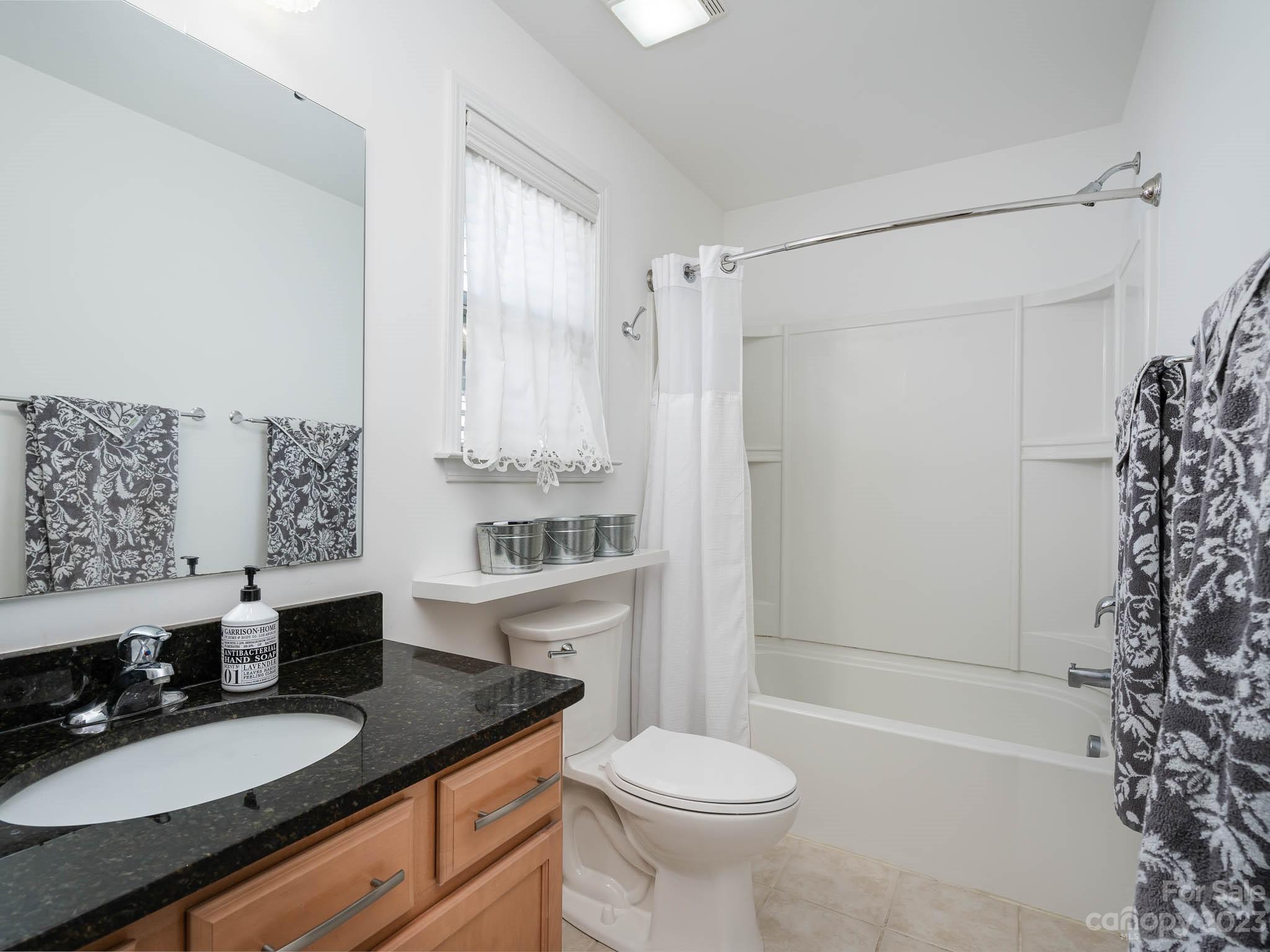 2185 Bluebell Way Tega Cay, SC 29708 - Photo 27 of 45 a bathroom with a granite countertop sink toilet a mirror a bathtub and shower