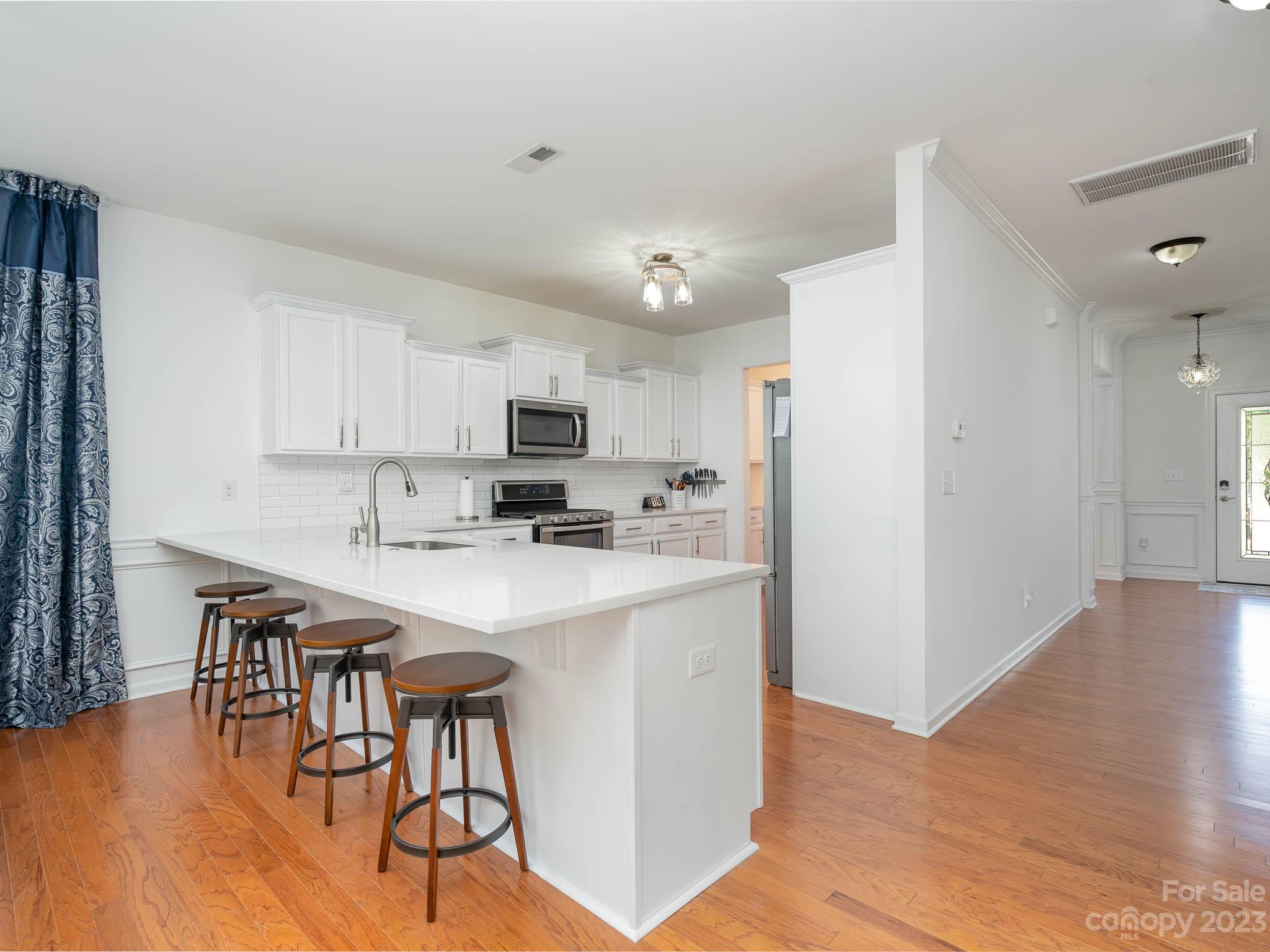 2185 Bluebell Way Tega Cay, SC 29708 - Photo 9 of 45 a kitchen with stainless steel appliances a table chairs refrigerator and microwave
