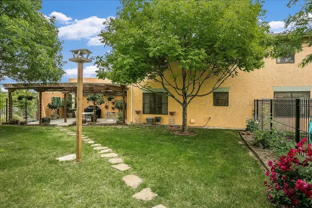 a view of a backyard with table and chairs potted plants and a large tree