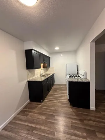 a living room with stainless steel appliances kitchen island sink and wooden floor