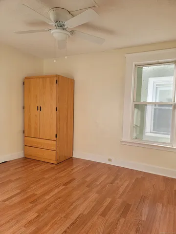 an empty room with wooden floor cabinet and windows