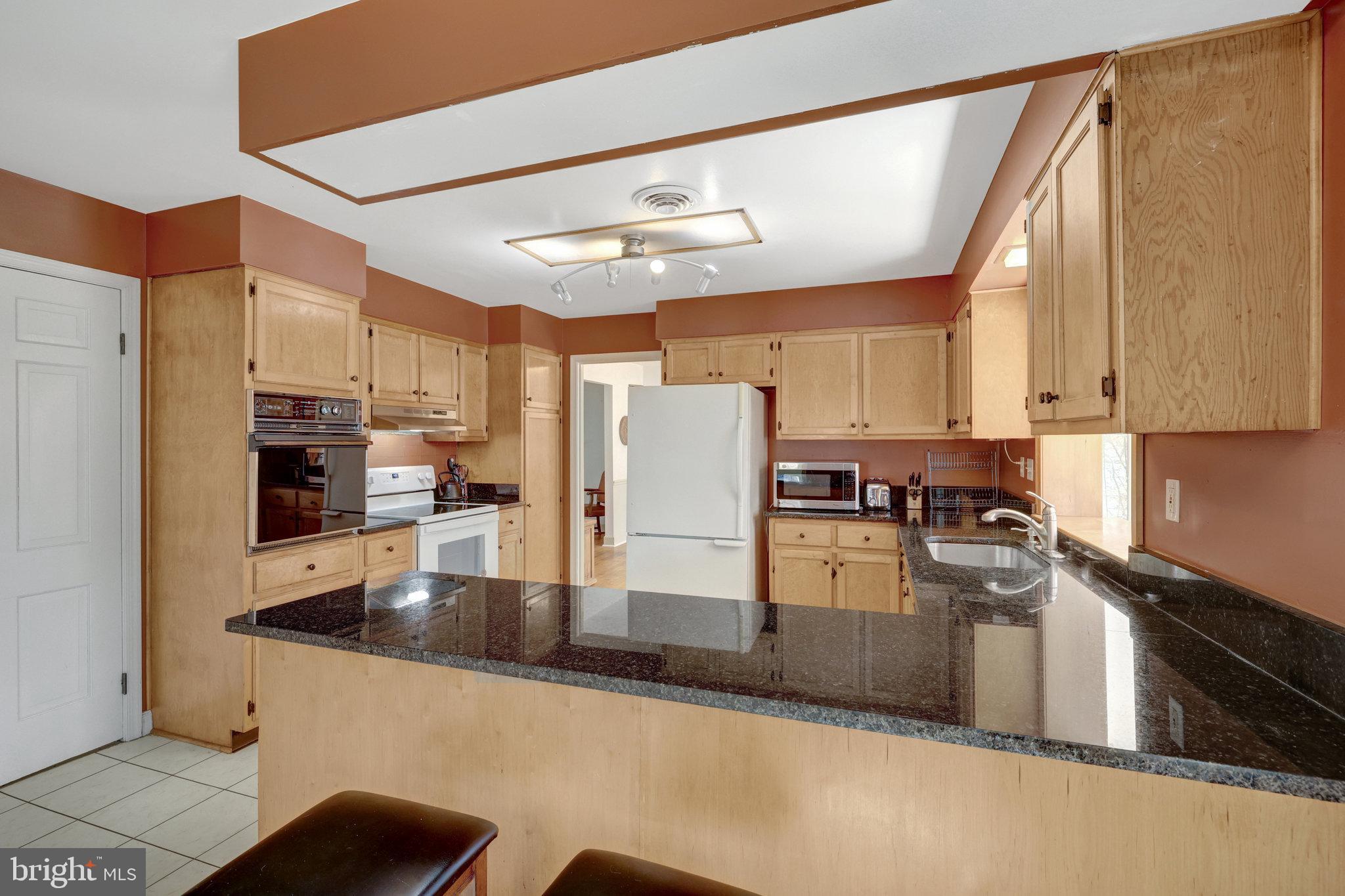 11332 Vale Road Oakton, VA 22124 - Photo 19 of 52 a kitchen with stainless steel appliances granite countertop a refrigerator a stove and white cabinets with wooden floor