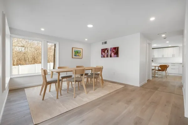 a kitchen with a table chairs wooden floors and white stainless steel appliances