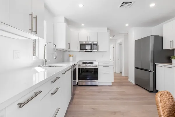 a kitchen with stainless steel appliances a refrigerator sink and wooden floor