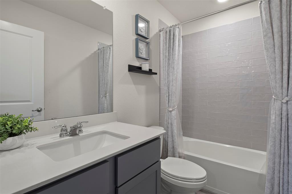 4125 Fern Loop Forney, TX 75126 - Photo 26 of 40 Bathroom featuring a built-in vanity with an integrated sink, polished chrome faucet, a white bathtub, and subway tile shower surround