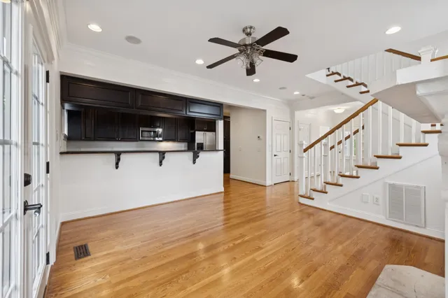 a view of a livingroom with an empty space wooden floor and a ceiling fan