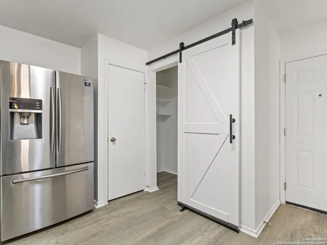 a view of a refrigerator in kitchen and white wooden cabinets