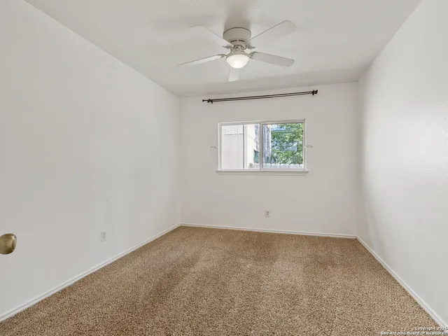 an empty room with windows and ceiling fan view